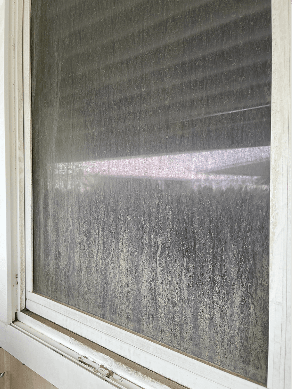 Dirty window with grime and water stains obscuring the view outdoors.