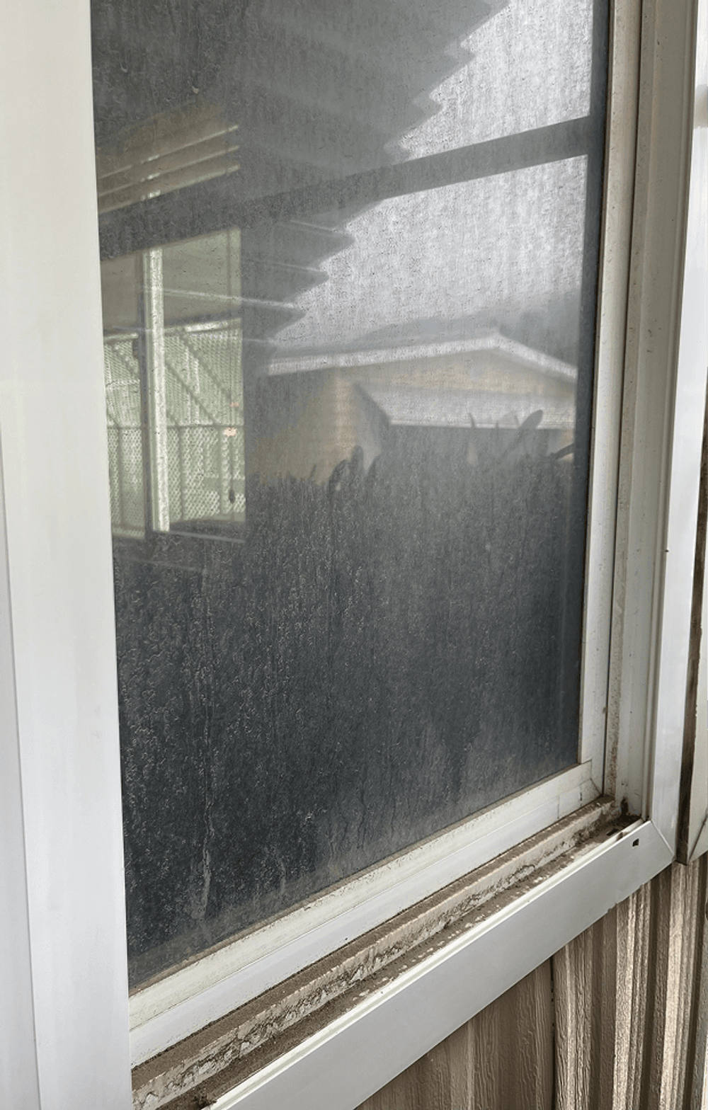 Dirty window showing foggy view of outdoor area and blurred background buildings.