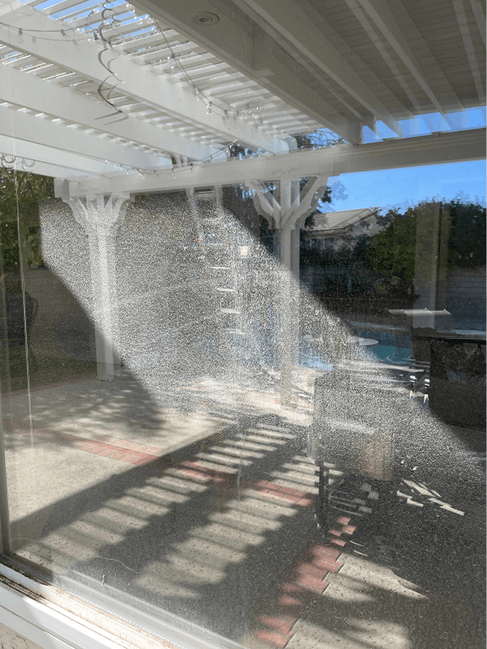 Reflection of patio area with sunlight streaming through a window, highlighting dust and furniture.